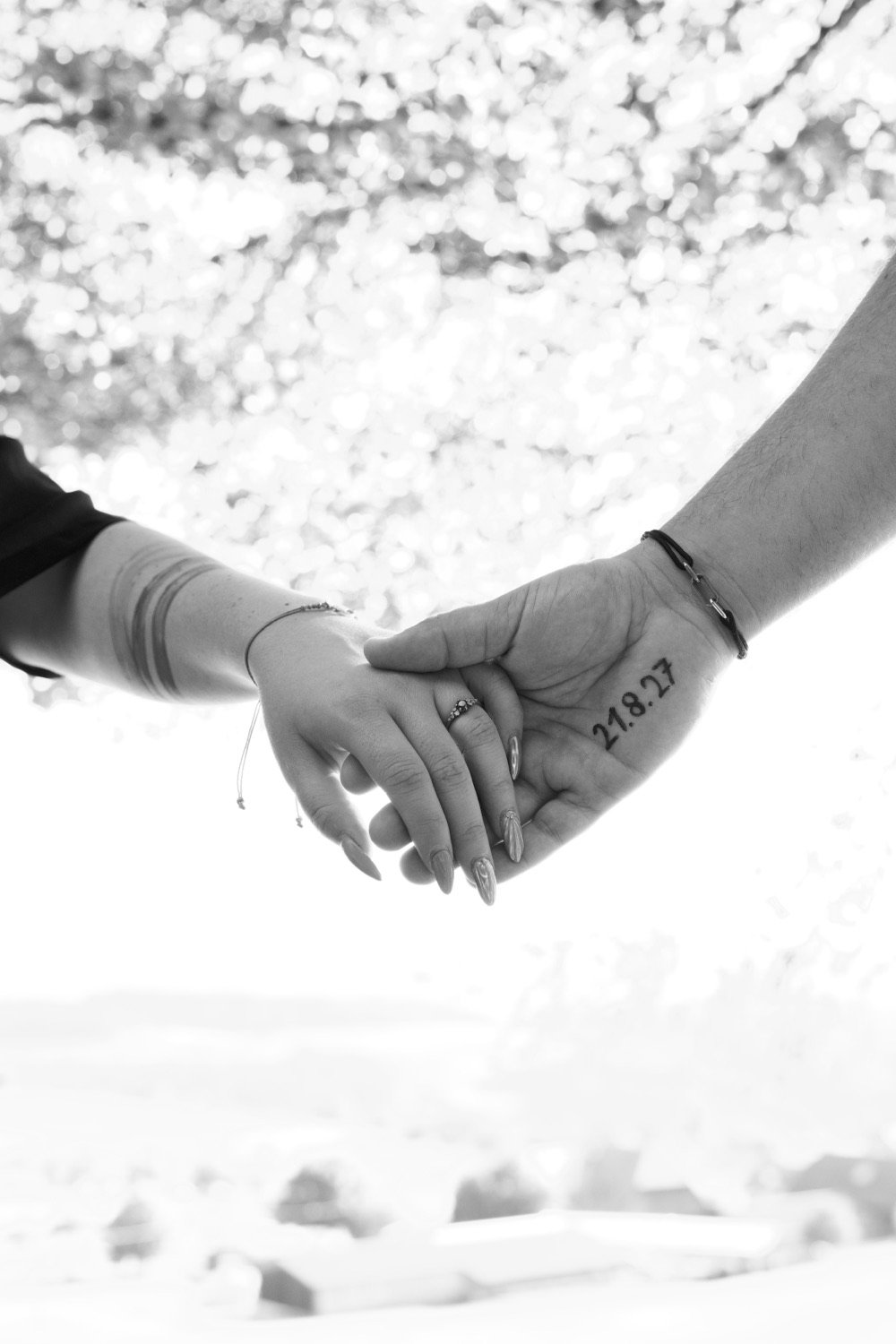 Schwarz-Weiss-Foto: Sarah und Silvan halten sich an den Händen, auf Silvans Hand steht „21.8.27“.